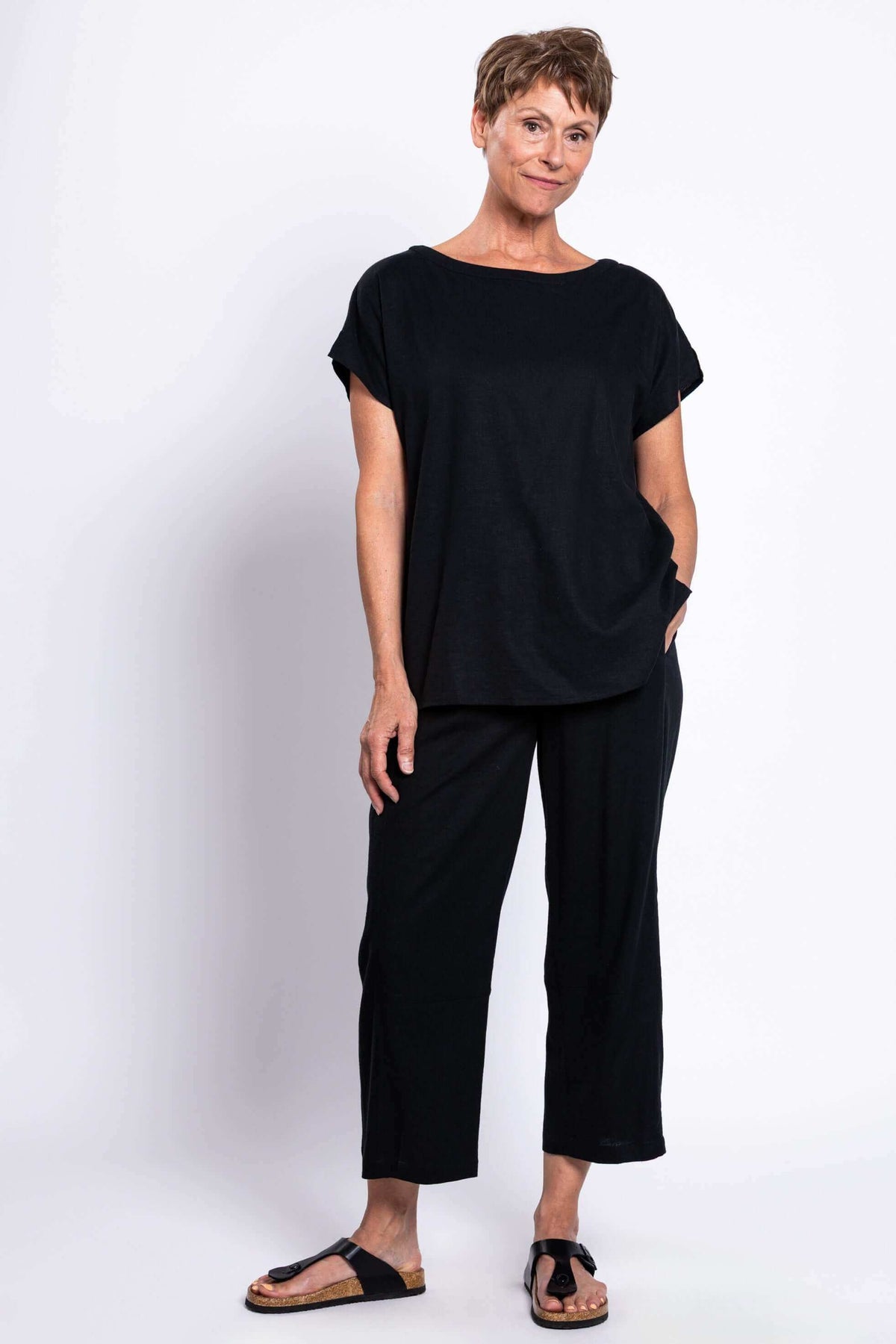 Woman standing in black linen blend tee and pants, hands in pockets
