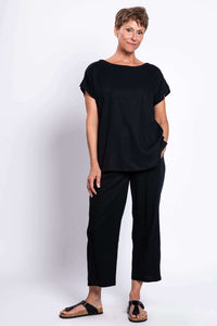 Woman standing in black linen blend tee and pants, hands in pockets