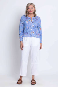 Woman standing in a blue floral cardigan and white pants, facing forward