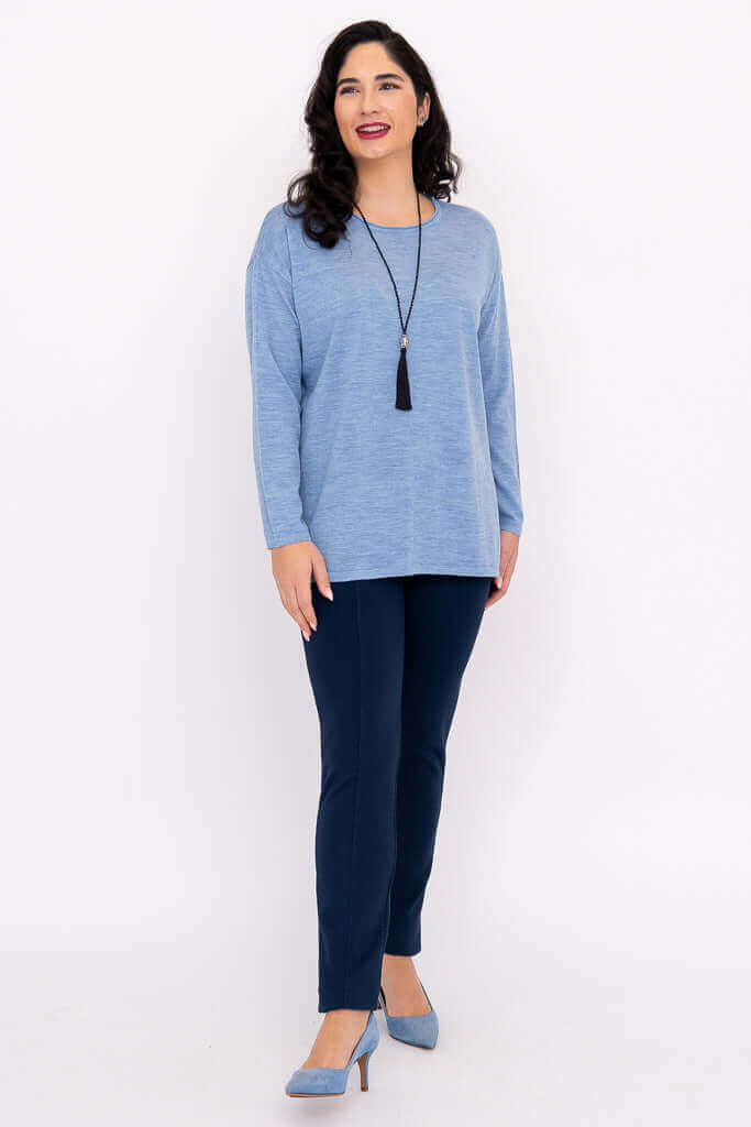 Woman with long dark hair smiling in a blue merino wool sweater and navy pants