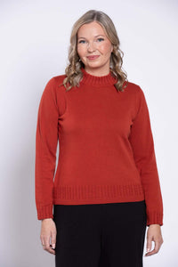Front view of a woman wearing a rust red mock neck cotton sweater with cable knit details