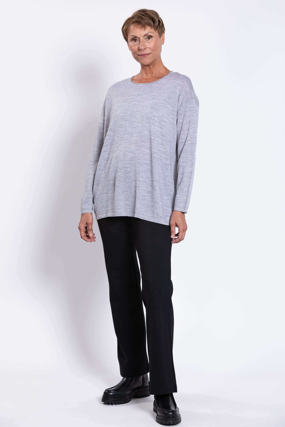Woman posing in a light grey Merino wool sweater and black pants