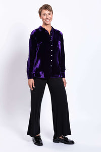 Woman smiling and modeling purple silk velvet blouse in a relaxed stance