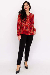 Woman modeling red flower print tailored blouse and black pants, standing and smiling