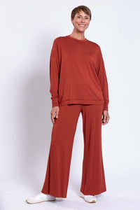 Woman posing with relaxed rust bamboo crew neck top and matching pants