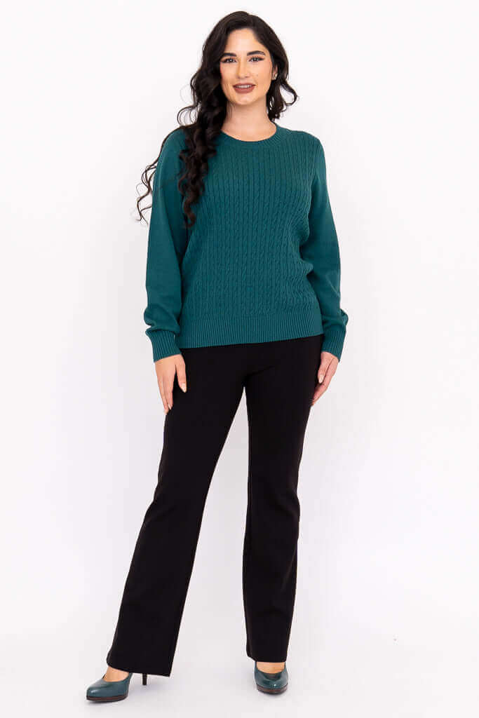 Woman posing in teal cable knit sweater and black dress pants