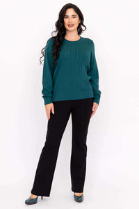 Woman posing in teal cable knit sweater and black dress pants