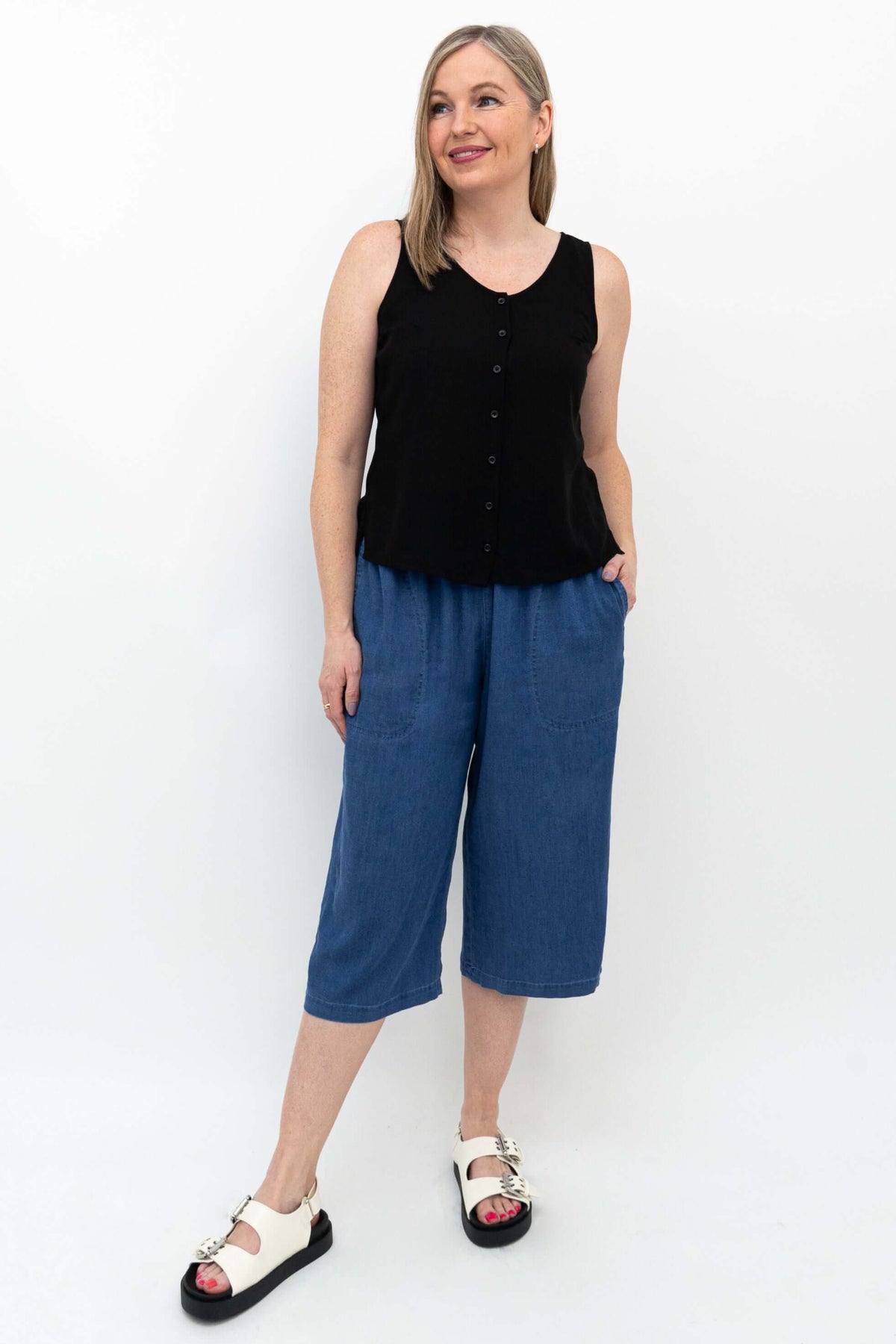 Woman smiling and posing in blue flowy tencel denim capris