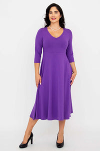 Woman posing confidently in a purple midi dress with black heels