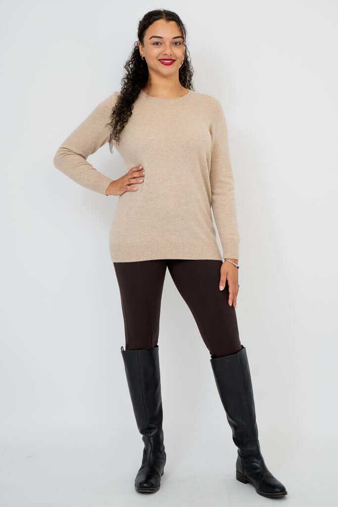 Woman posing in beige sweater with hand on hip