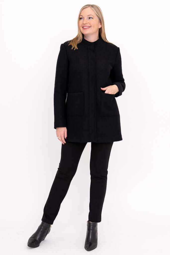Woman posing in black boiled wool coat with hands in pockets
