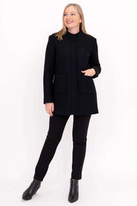 Woman posing in black boiled wool coat with hands in pockets