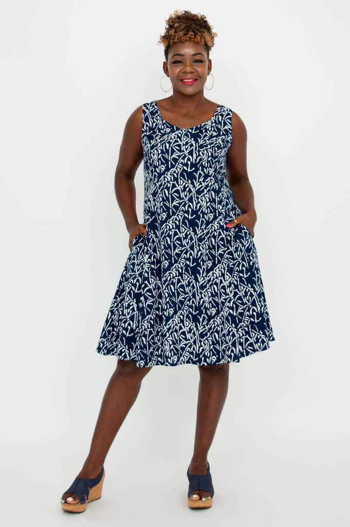 Woman posing in a navy and white sleeveless dress with hands in pockets