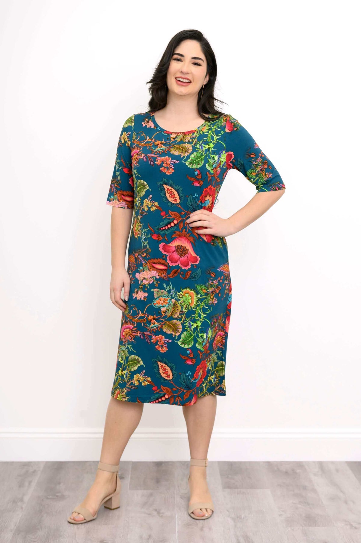 Model smiling in a colorful knee-length bamboo dress with floral pattern, hands on hips