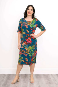 Model smiling in a colorful knee-length bamboo dress with floral pattern, hands on hips
