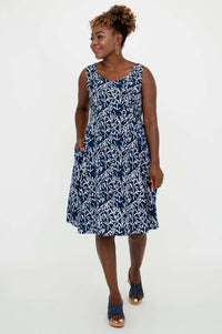 Woman smiling in a navy and white sleeveless dress with hands in pockets