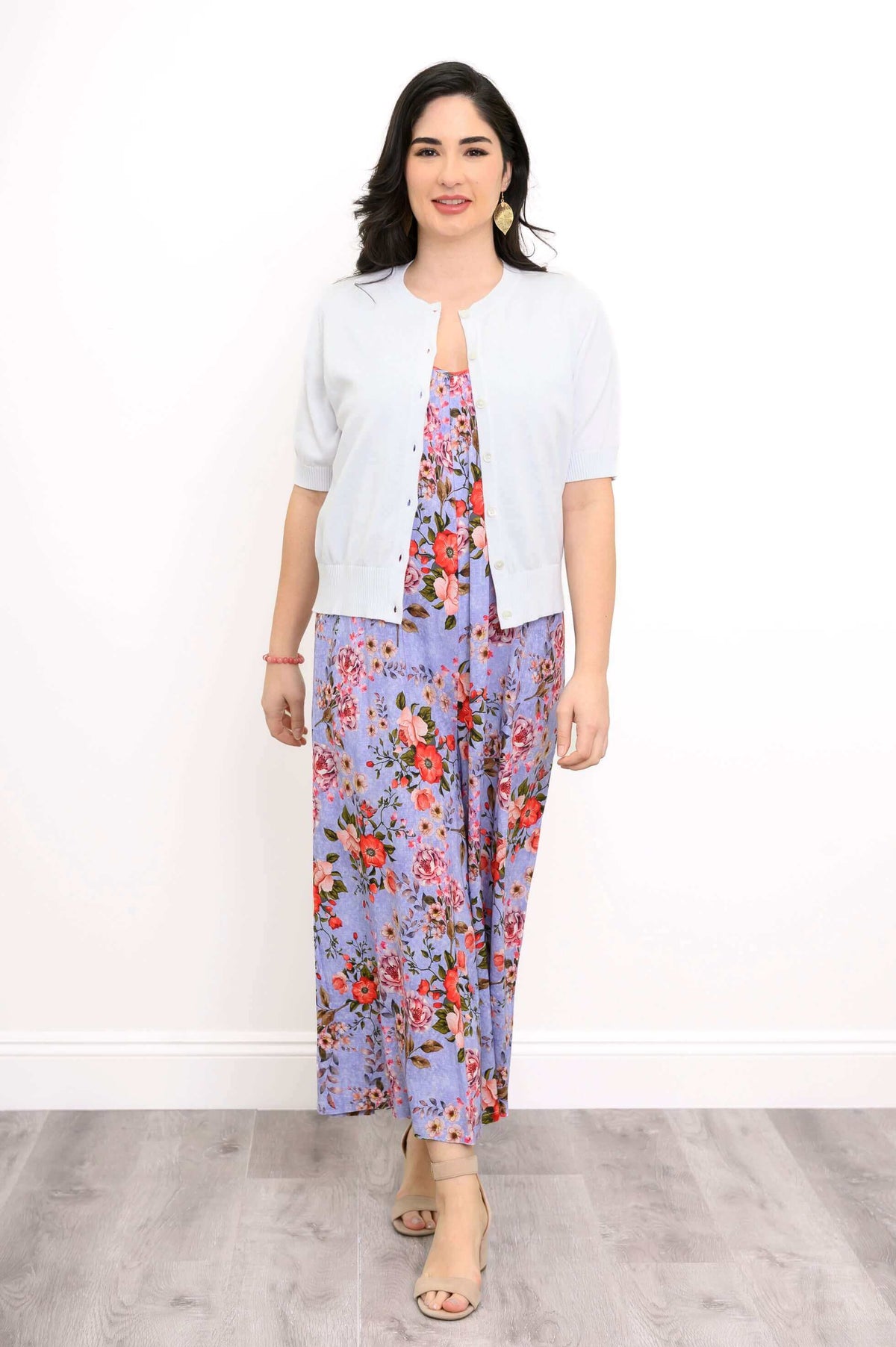 Woman in a light cardigan over a purple floral jumpsuit with red flowers