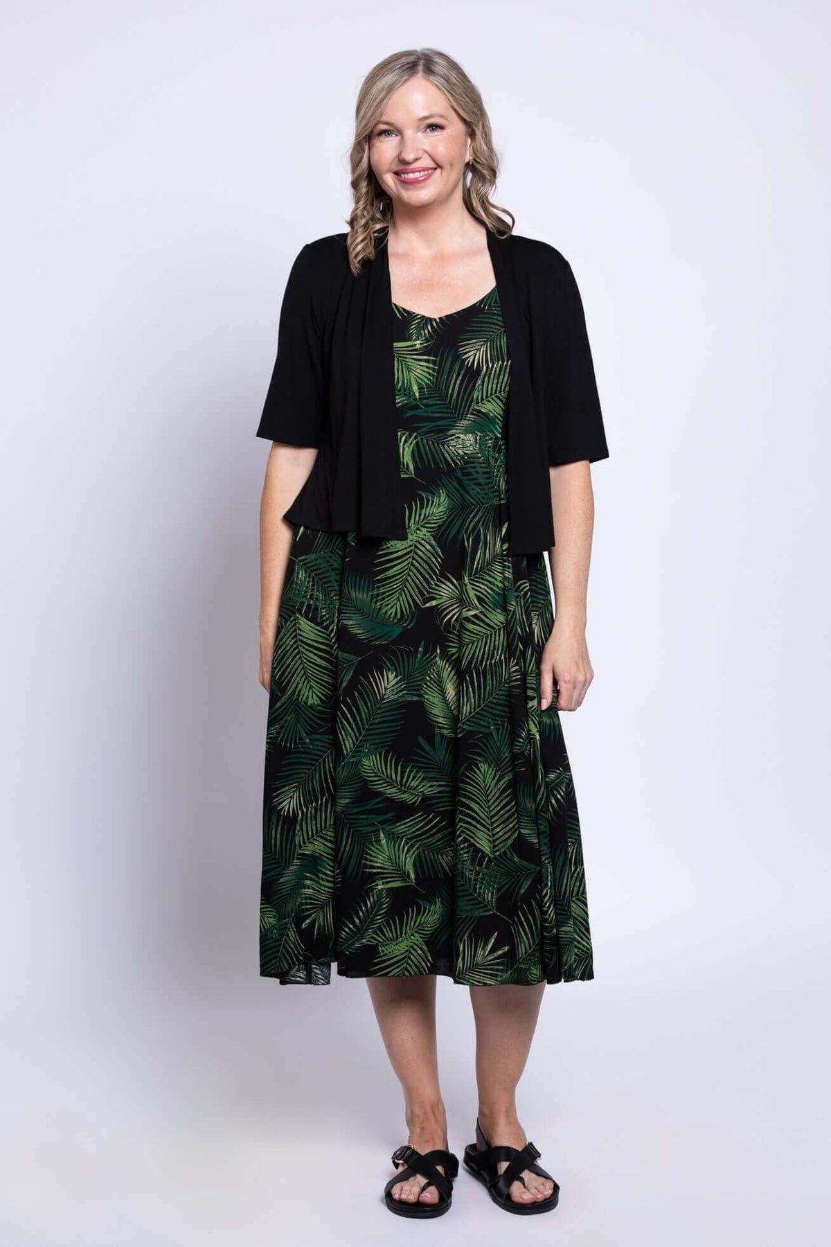 Woman in a green palm leaf dress styled with a black shrug, front view