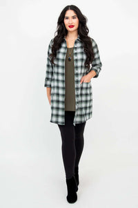 Woman styling a green plaid flannel tunic shirt open over a top, hand in pocket