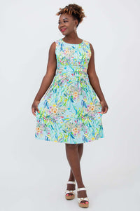 Woman twirling in blue floral ruched dress with a vibrant print