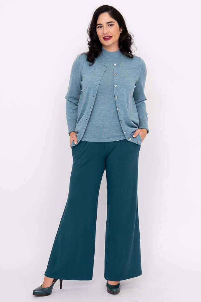 Woman wearing Kitten Cardigan and teal pants with hands in pockets