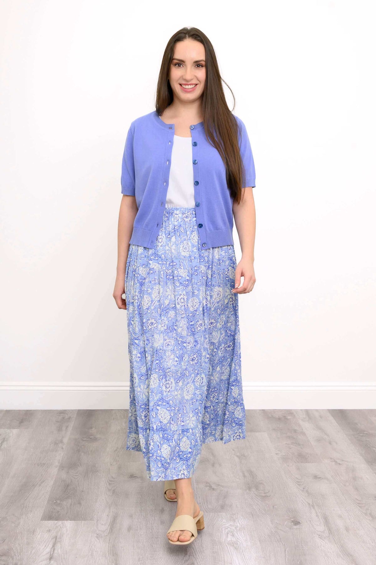 Woman wearing a blue tiered maxi skirt with a purple cardigan and sandals