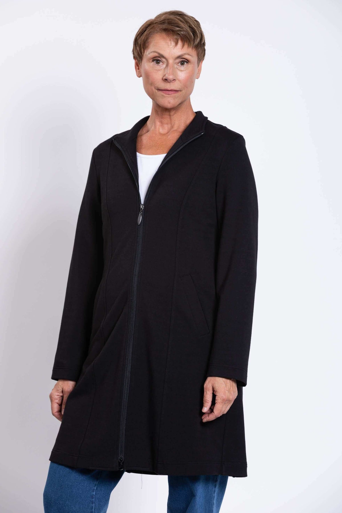 Woman wearing a black long zip-front coat with princess seams and pockets
