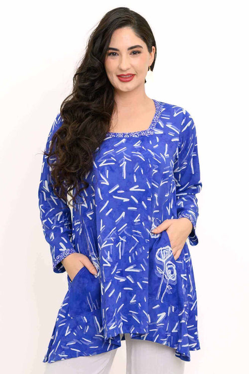 Woman wearing a blue shark-bite hem tunic with white abstract print and square neckline