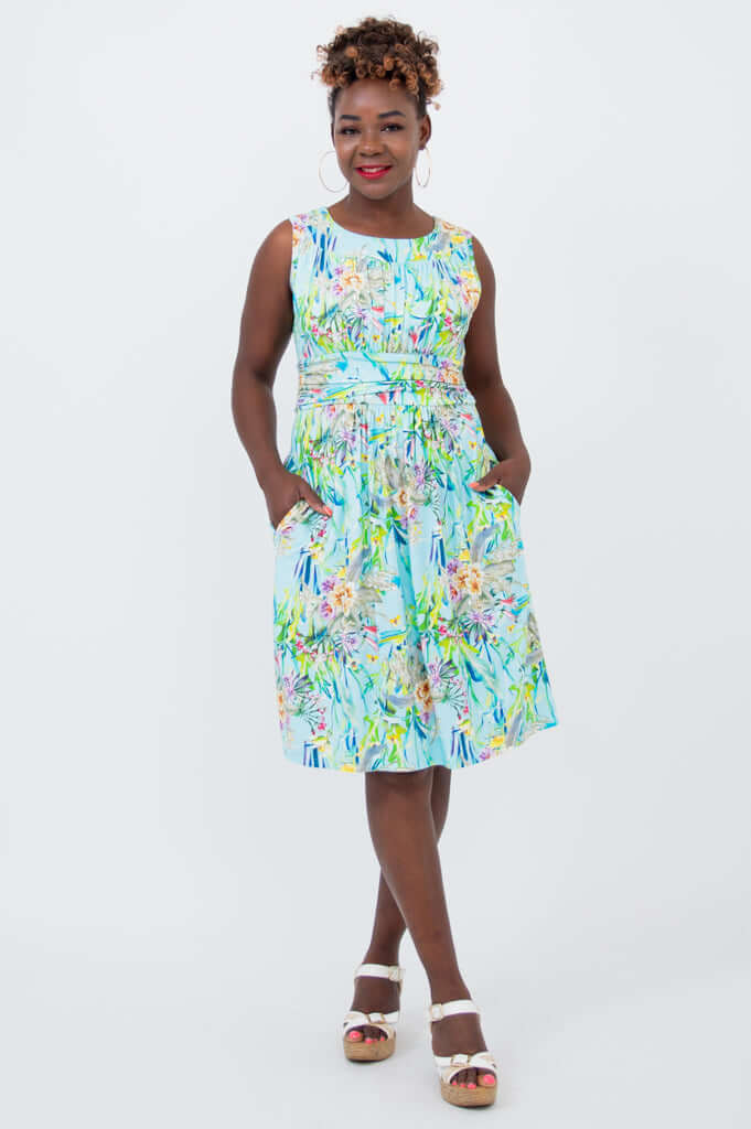 Woman wearing a sleeveless blue floral ruched dress with pockets