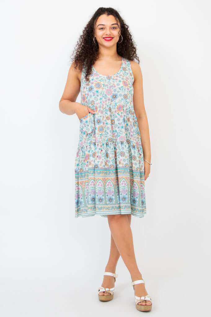 Woman wearing a sleeveless floral tiered dress with scoop neckline and pockets