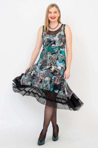 Woman wearing a sleeveless printed dress with mesh hem, holding skirt to side
