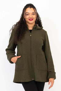 Woman wearing an olive green wool blend coat with hands in pockets