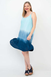 Woman wearing an ombre aqua tiered sundress twirling and smiling