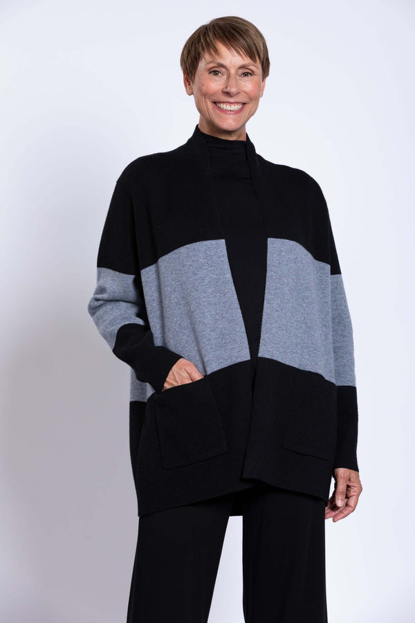 Woman wearing black and grey colour-block open shawl sweater, smiling front view