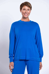 Woman wearing a vibrant blue relaxed crew neck top with drop shoulders and long sleeves