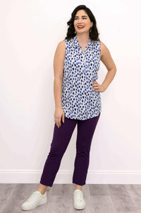 Woman in blue spotted sleeveless collared tank top, hand on hip, smiling
