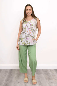 Full-body view of woman in floral botanical sleeveless tank top and green pants