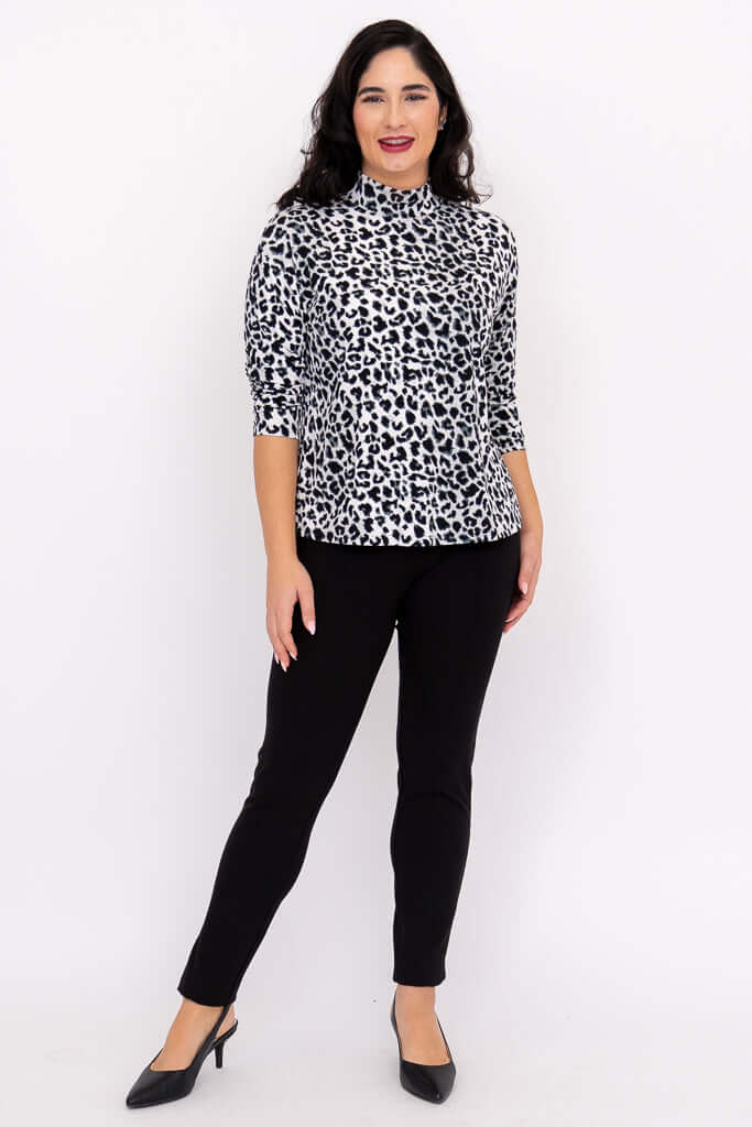 Woman posing in leopard print mock neck top with hands at sides