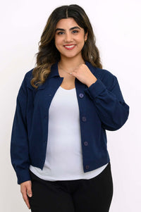 Woman wearing a navy blue button-up jean jacket over a white top, cropped view