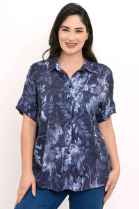 Woman wearing a navy blue floral button-up blouse with dolman sleeves, front view