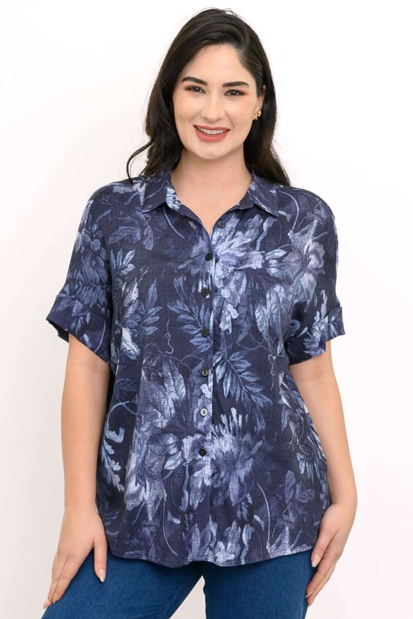 Woman wearing a navy blue floral button-up blouse with dolman sleeves, front view
