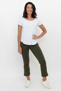 Woman wearing olive green crop pants and a white t-shirt, front view