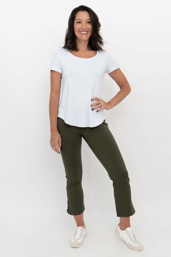 Woman wearing olive green crop pants and a white t-shirt, front view