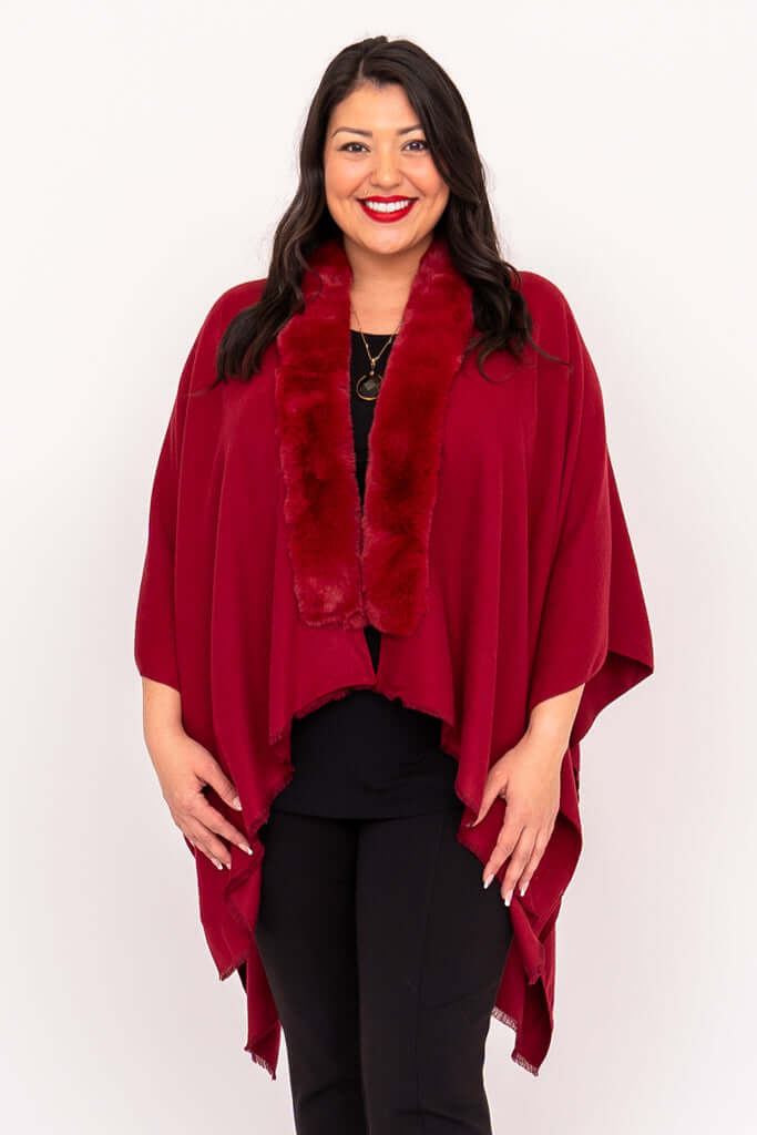 Woman wearing a deep red wrap with faux fur collar, smiling and facing forward