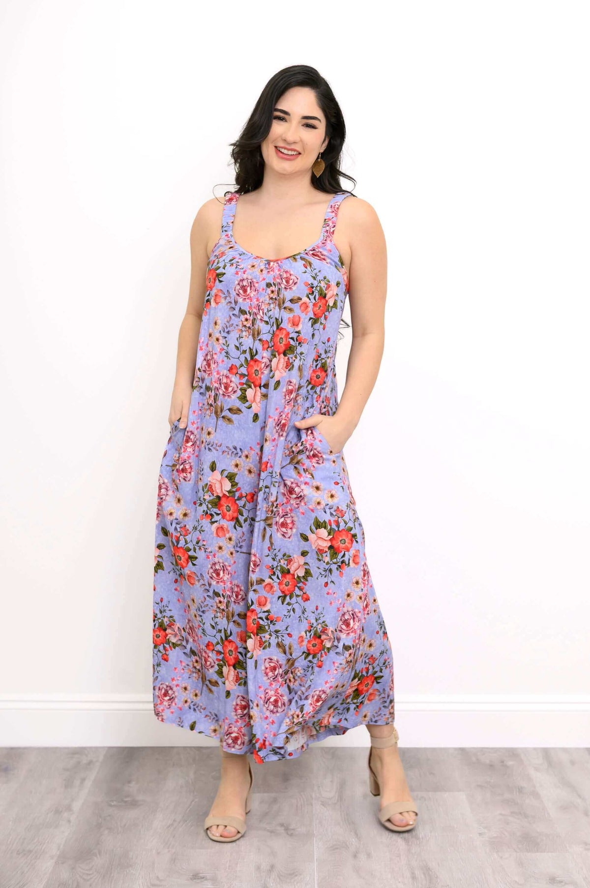 Woman wearing a sleeveless purple floral jumpsuit with pockets, smiling