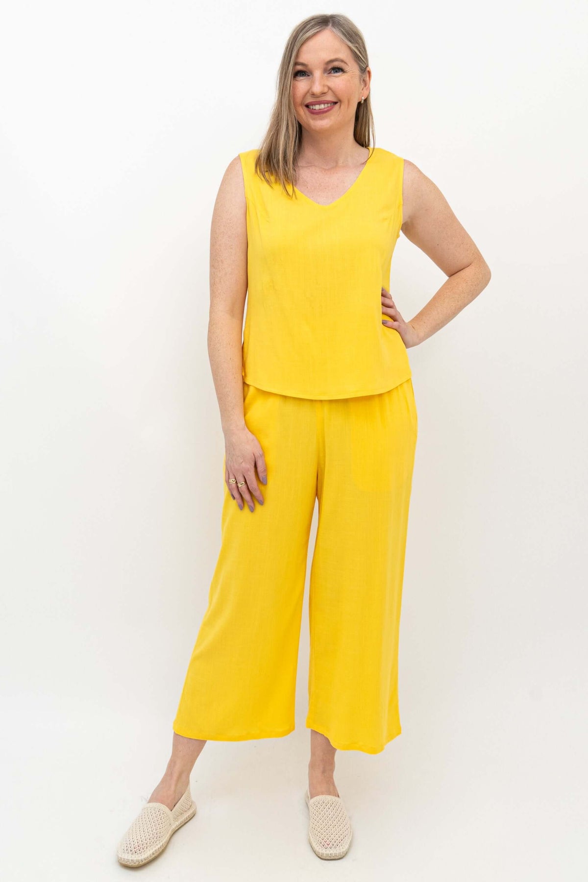 Woman modeling yellow capri pants and matching sleeveless top, smiling
