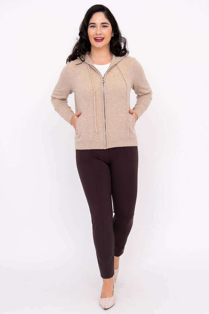 Woman with hands in hoodie pockets, smiling, front view