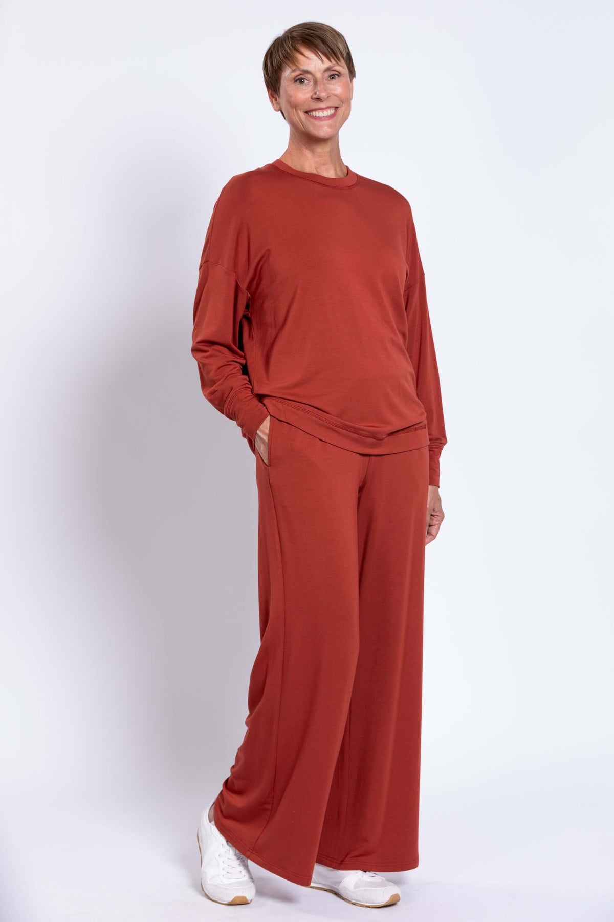 Woman with hand in pocket wearing rust bamboo crew neck top and wide leg pants