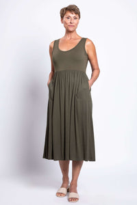 Woman with hands in pockets wearing an olive green empire waist midi dress