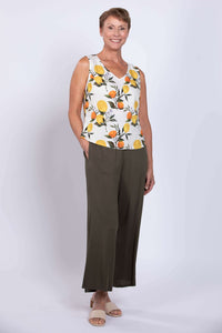 Angled full front view of woman wearing lemon print cropped tank and olive pants